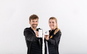 Zwei Personen. Links ein Mann mit einem Smartphone in der Hand und rechts eine Frau mit einer Steckdose in der Hand.