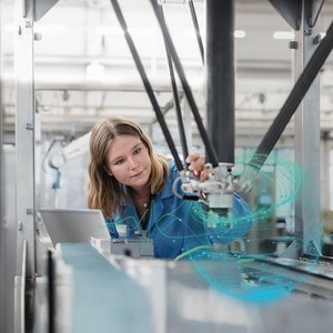 Junge Frau in einem blauen Kittel mit technischen Gerätschaften.